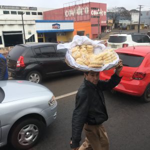 A street vendor weaves in between cars, deftly balancing a large basket of chipás